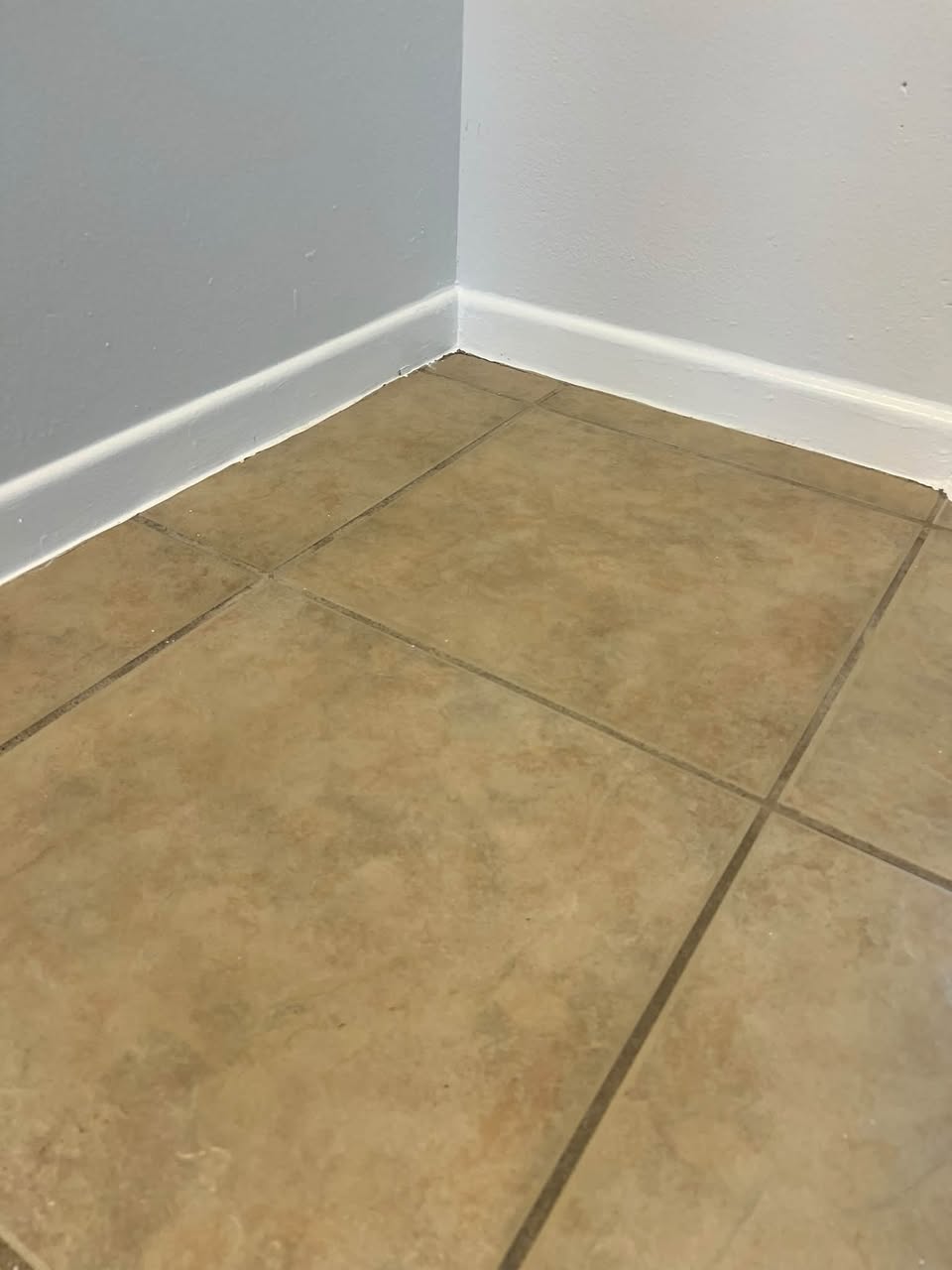 Tile floor and baseboard after a Crystal Bell's deep clean: bright tile and clean grout
