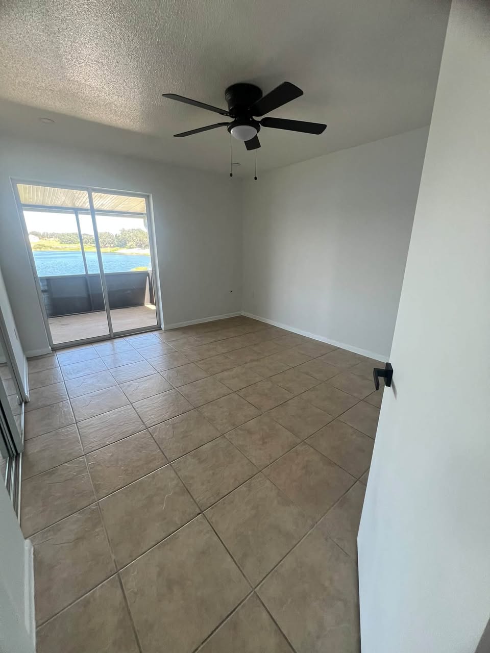 Empty bedroom with clean tile floors and a lake view, ready for move-in